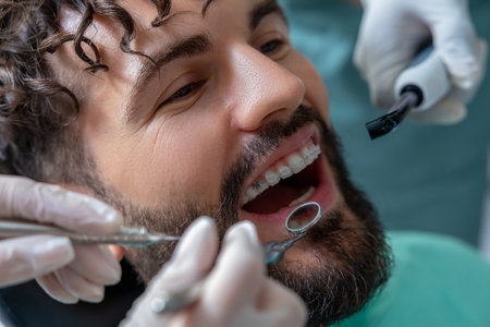 Patient in dental chair receiving oral examination or professional treatment from skilled dentistの写真素材