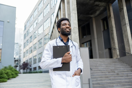 Man doctor with beard holding clipboard with medical documents posing near modern clinicの写真素材
