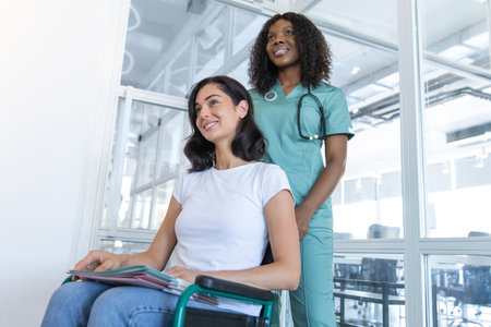 African american female doctor with a patient in a wheelchair in the clinic corridorの写真素材