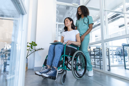 African american female doctor with a patient in a wheelchair in the clinic corridorの写真素材