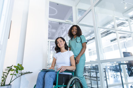 African american female doctor with a patient in a wheelchair in the clinic corridorの写真素材