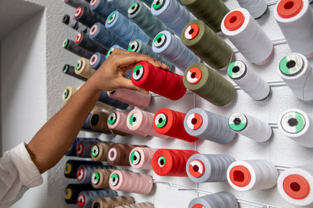 Unrecognizable woman dressmaker choosing colored threads in tailoring workshopの写真素材