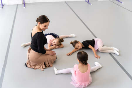 Pretty girls sitting on floor in ballet studio practicing stretching during classical dance trainingの写真素材