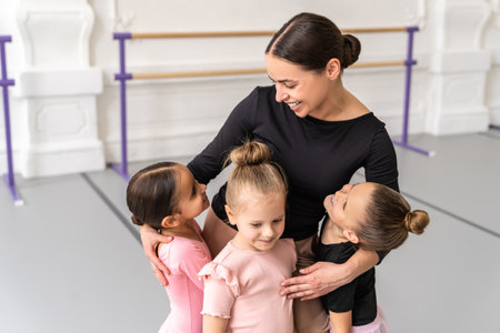 Graceful woman hugging cheerful group of little girls standing in studioの写真素材