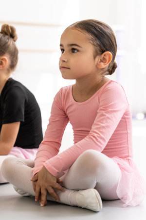 Little girl ballet dancer sitting on floor in dance class studioの写真素材