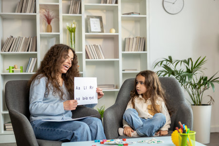 Long-haired female speech therapist showing pictures to a long-haired little patientの写真素材
