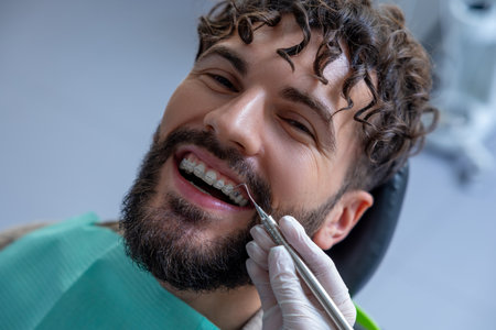 Doctor in dental clinic wearing gloves carefully inspecting patientâ€™s mouth with precise...