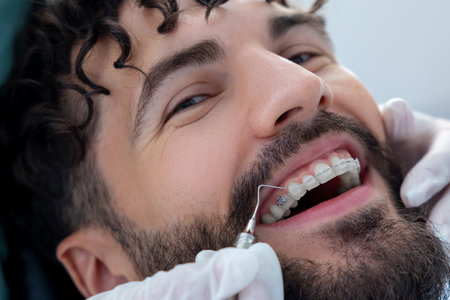 Doctor in dental clinic wearing gloves carefully inspecting patientâs mouth with precise instrumentsの写真素材