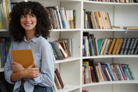 Sweet curly-haired young girl at the bookshelves in the library
