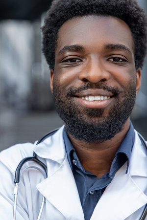 Bearded man doctor wearing medical uniform and stethoscope standing outside clinic