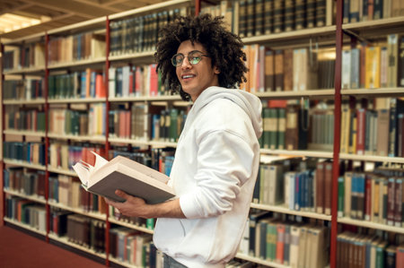 Curly-haired young man in eyeglasses in the library