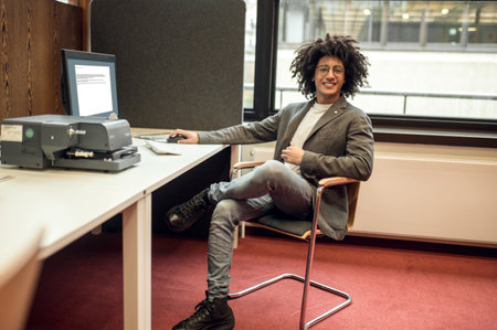 Young curly-haired businessman in the office looking confident