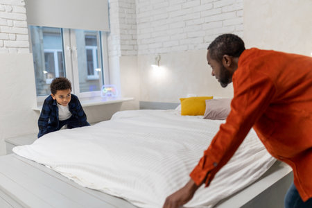 Father and son making bed in the morning together