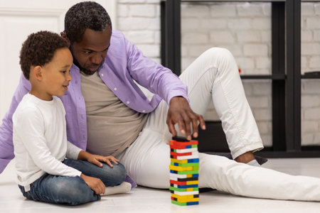 African american family sitting on the floor and playing jengaの写真素材