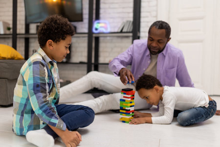 African american family sitting on the floor and playing jengaの写真素材