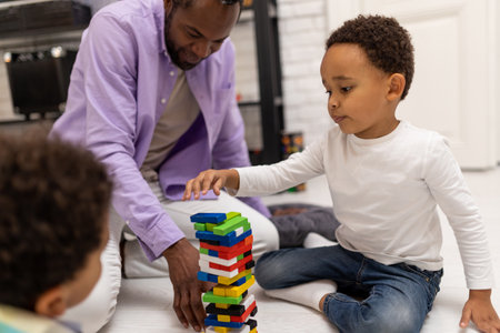 African american bearded man looking involved while playing with his sonsの写真素材