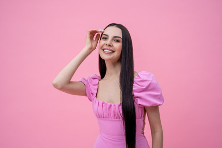 Pretty long-haired young woman in pink dress on a pink backgroundの写真素材