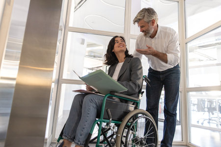Man with disabled colleague standing at the elevator for inclusionの写真素材