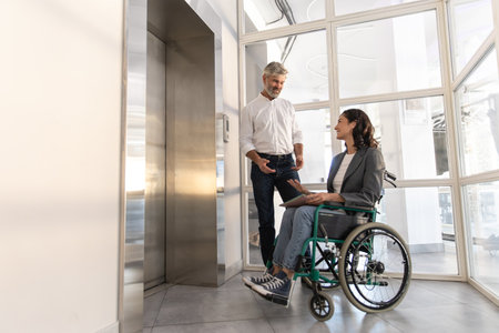 Businesswoman with disabilities with man posing in office hallの写真素材