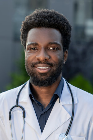 African American doctor standing outside hospital wearing uniform resting after hard day