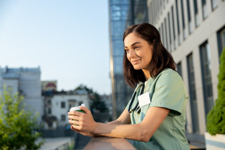 Pretty young female doctor having coffee and looking contentedの写真素材