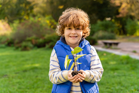 Boy child planting small sprout in garden on Earth Day taking care for environmentの写真素材
