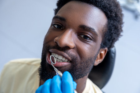 Male dentist inspecting patientâs teeth with mirror providing essential treatment during the checkupの写真素材