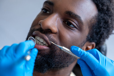 Skilled dentist in dental clinic using instruments to inspect patients teethの写真素材
