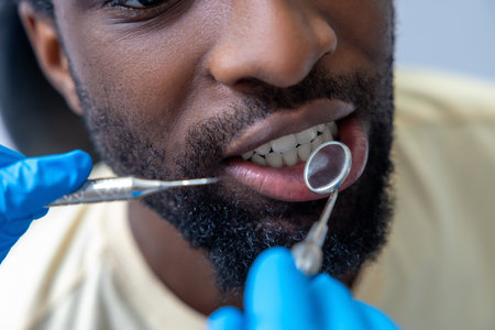 Professional dentist in modern office checking patients gums with dental toolの写真素材