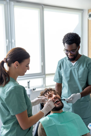 Orthodontist conducting dental checkup in modern clinic examining patients teethの写真素材