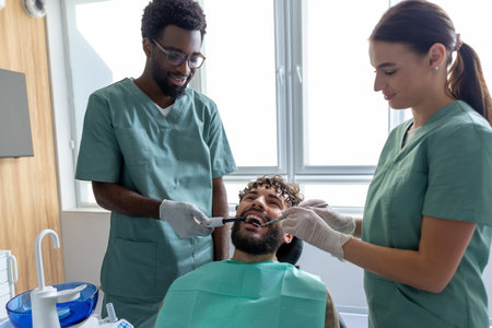 Male dentist examining patientâ€™s teeth during checkup in dental office using orthodontic...