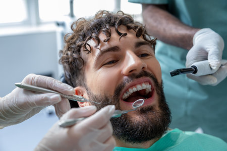 Male dentist performing orthodontic checkup on patient in modern dental clinicの写真素材