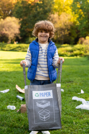 Volunteer little boy collecting paper garbage in parkの写真素材