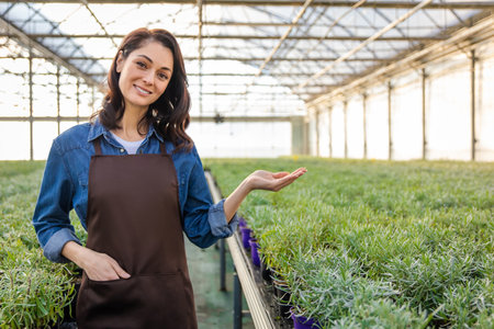 Dark-haired young woman in apron in a greenhouseの写真素材
