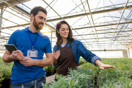 Two colleagues exploring the greenhouse plants and looking involvedの写真素材