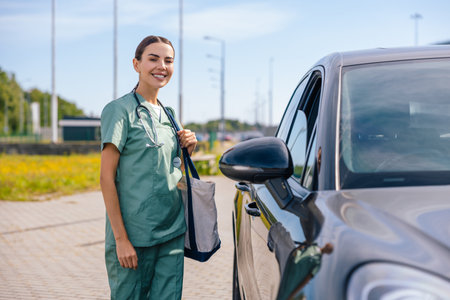 Smiling young woman in green medical uniform standing at the carの写真素材