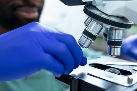 Unrecognizable male scientist in lab using lens of microscope for study and research on healthの写真素材