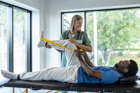 Female doctor helping a male patient during exercising with stretch bandの写真素材