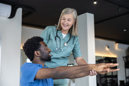 Young male patient exercising with physical therapist and stretching his armsの写真素材