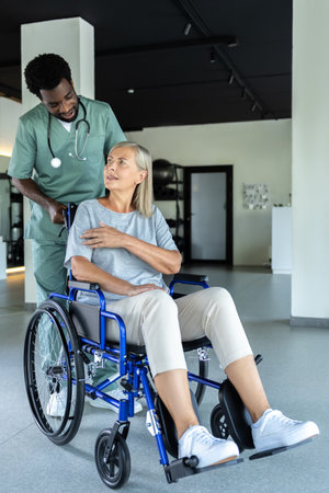 Doctor helps elderly woman in wheelchair and gives encouraging talkの写真素材