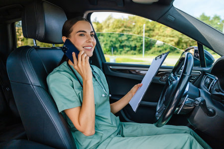 Female doctor sitting in the car and talking to the patient on the phoneの写真素材