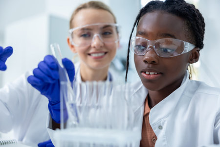 Medical woman and her colleague in laboratory using pipette conducting experiment on samplesの写真素材