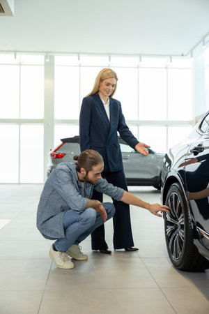 Male client examining wheels of a new car model in a dealershipの写真素材