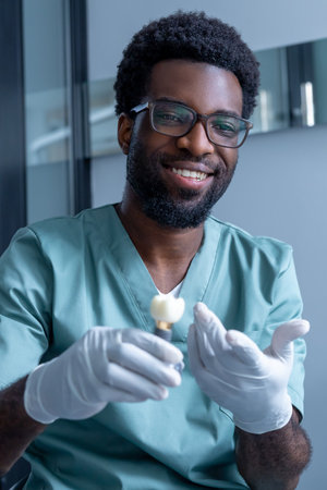 Male stomatologist showing implant during dental visit in modern dental clinic