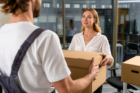 Worker of a delivery services office passing the package to the customerの写真素材