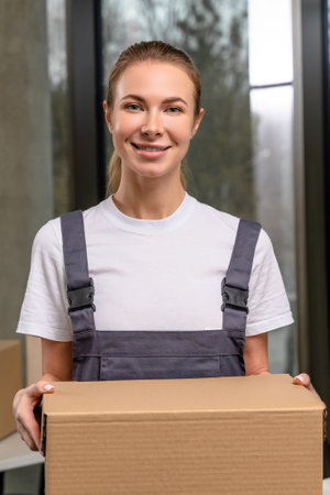 Smiling female packaging center worker with a parcel in handsの写真素材