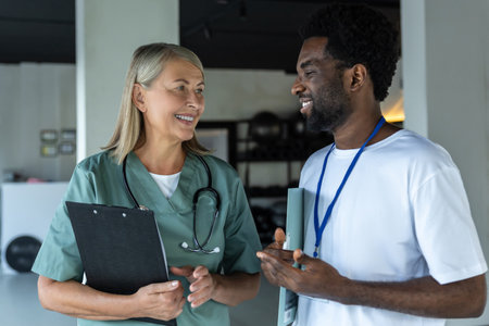 Female doctor in medical scrubs with an african american intern in the clinicの写真素材