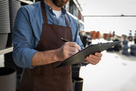 Man working seller in warehouse with pots for plants on shelves in retail storeの写真素材
