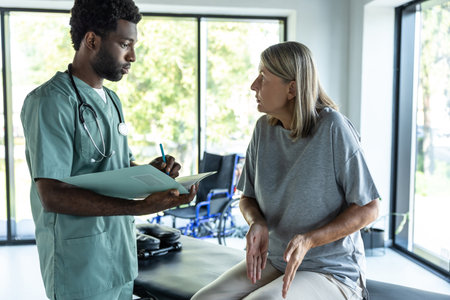 Dark-skinned young male doctor talking to a female patient in a rehabilitation clinic