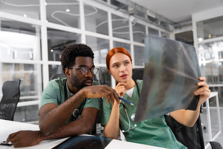 Diverse doctors collaborating on surgery discussing diagnosis and reading X-ray